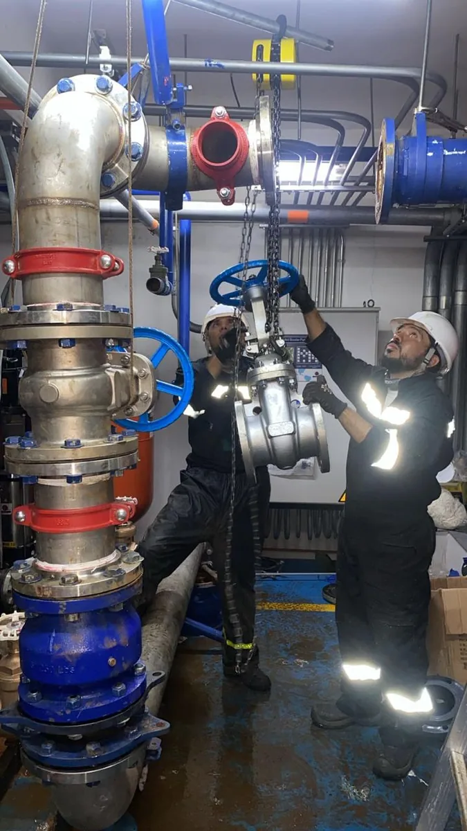 Técnicos de Servihidráulicos SAS instalando tubería y válvula en acero inoxidable en un cuarto de máquinas en Bogotá